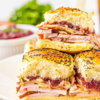 Layers of ham, turkey, cheese, and cranberry sauce in a fluffy roll slider