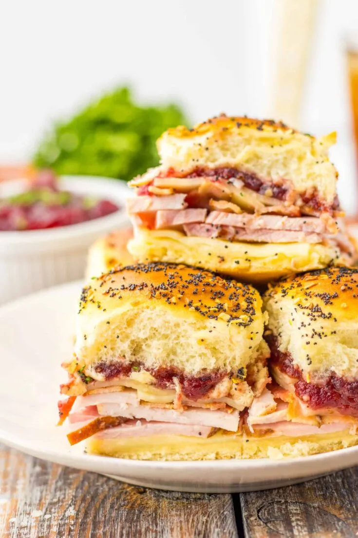 Layers of ham, turkey, cheese, and cranberry sauce in a fluffy roll slider