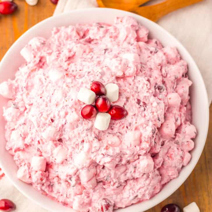 Creamy cranberry marshmallow salad in a white bowl, topped with cranberry and mini marshmallows.
