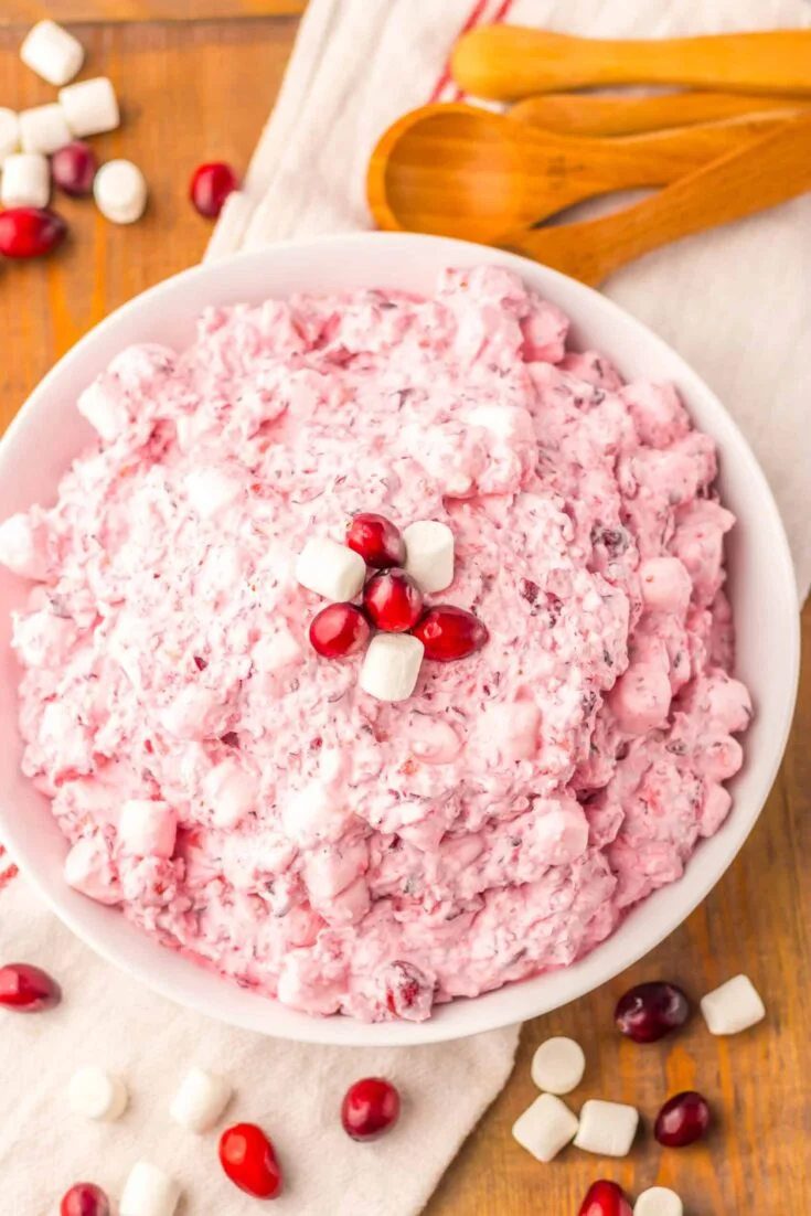 Creamy cranberry marshmallow salad in a white bowl, topped with cranberry and mini marshmallows.