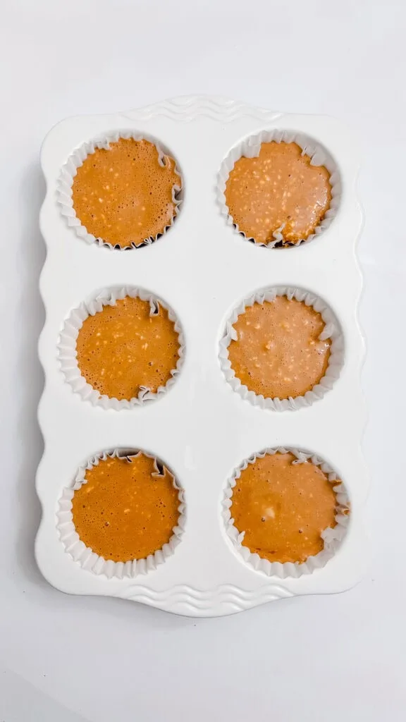 Filling cupcake liners with Gingerbread Cheesecake batter for baking.