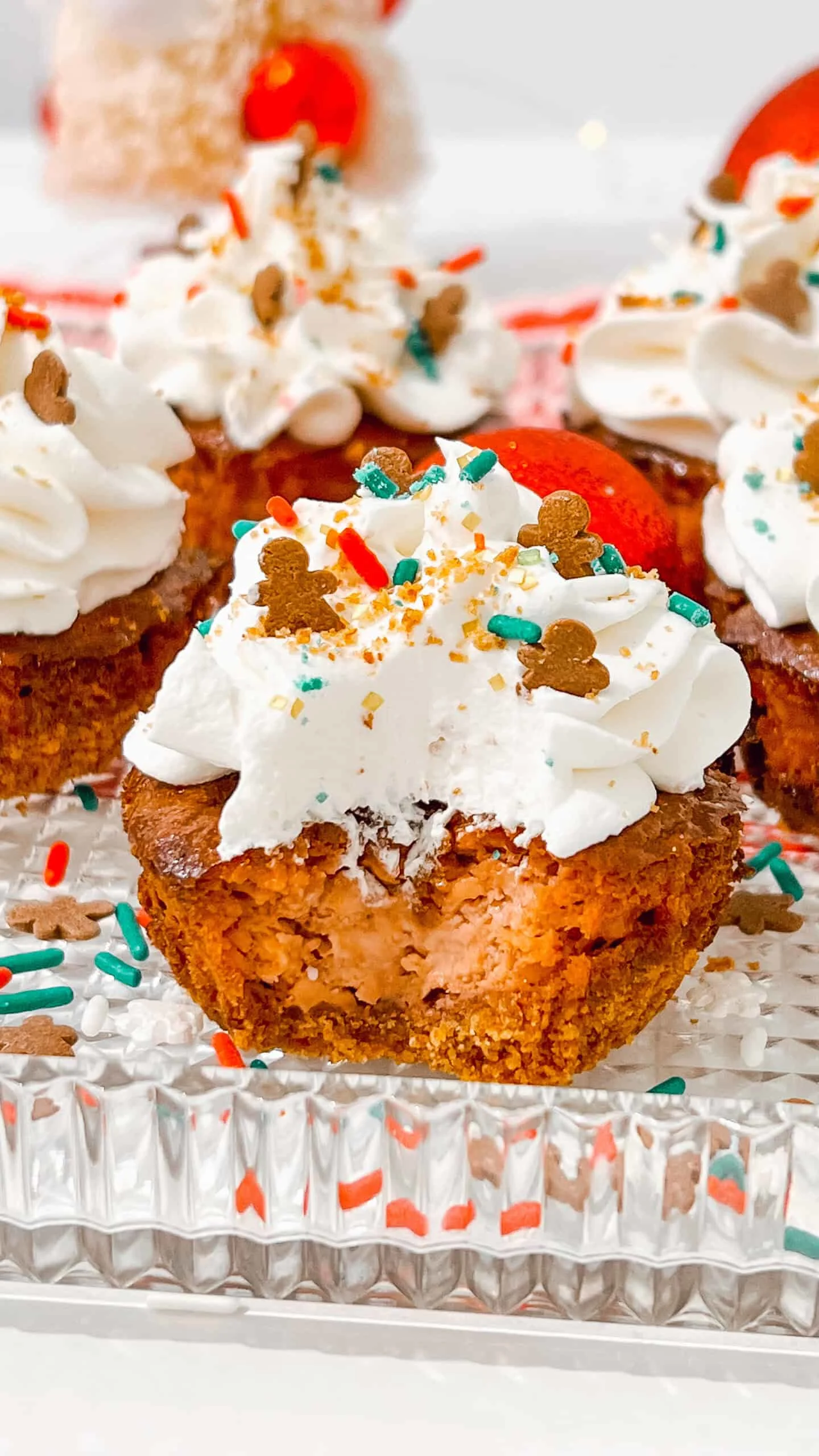 Gingerbread cheesecake cupcakes with whipped cream and colorful sprinkles, perfect for celebrations.