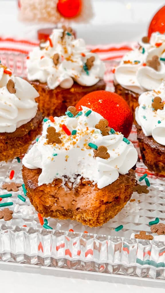 Mini Gingerbread Cheesecake Bites topped with whipped cream, sprinkles, and chocolate decorations.