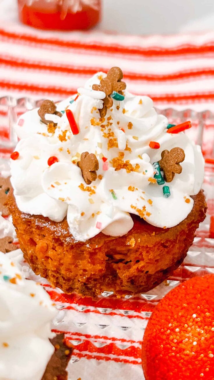 Gingerbread Cheesecake Bites cupcake with whipped cream, gingerbread men, sprinkles for holiday dessert.