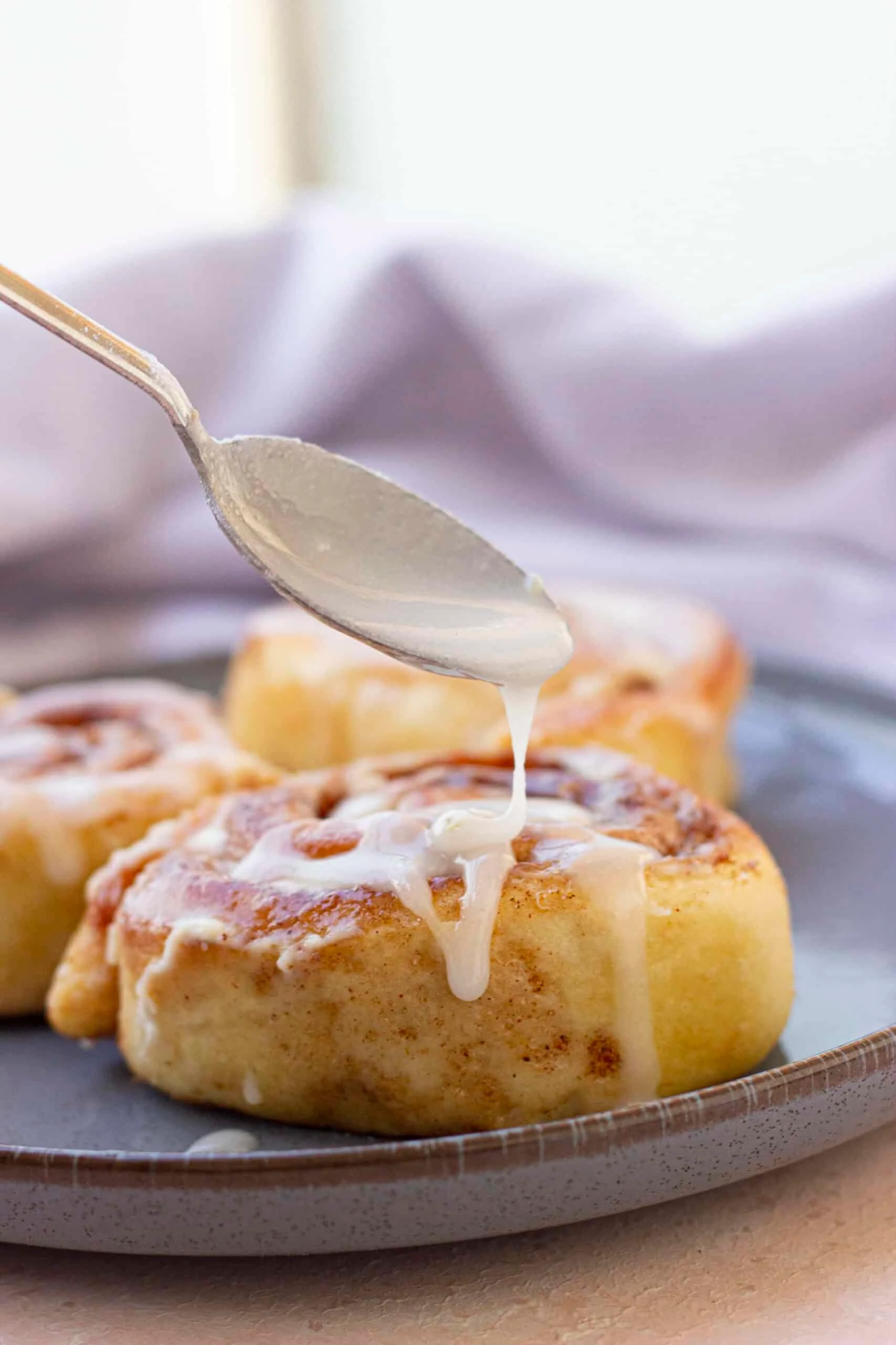 spoon drizzle glaze over cinnamon rolls