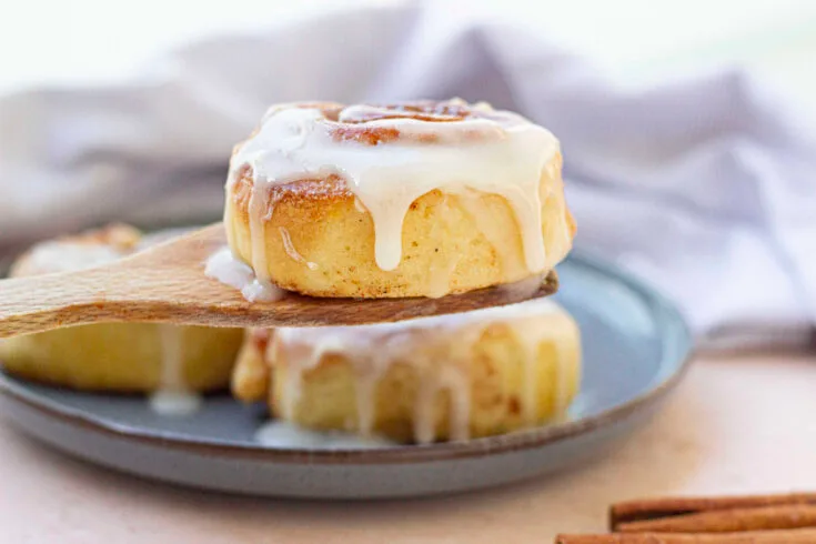 cinnamon roll on wooden spoon, cinnamon roll on blue plate