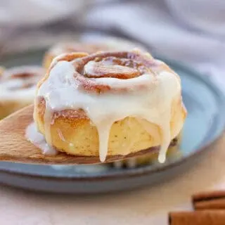 two cinnamon rolls on blue plate cinnamon sticks