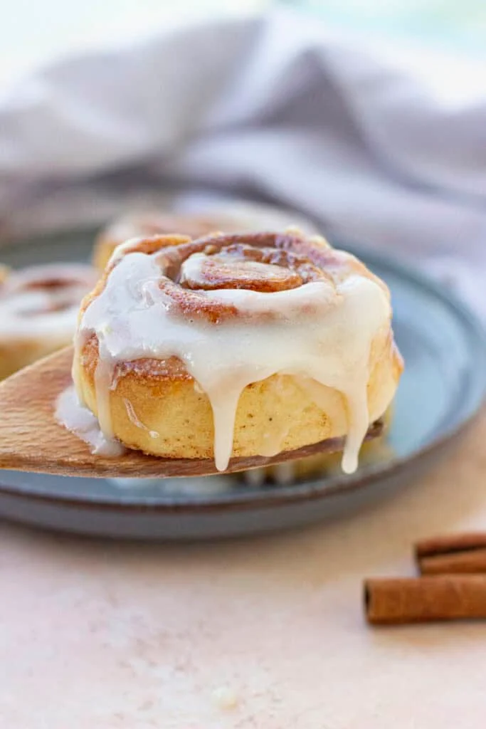 two cinnamon rolls on blue plate cinnamon sticks