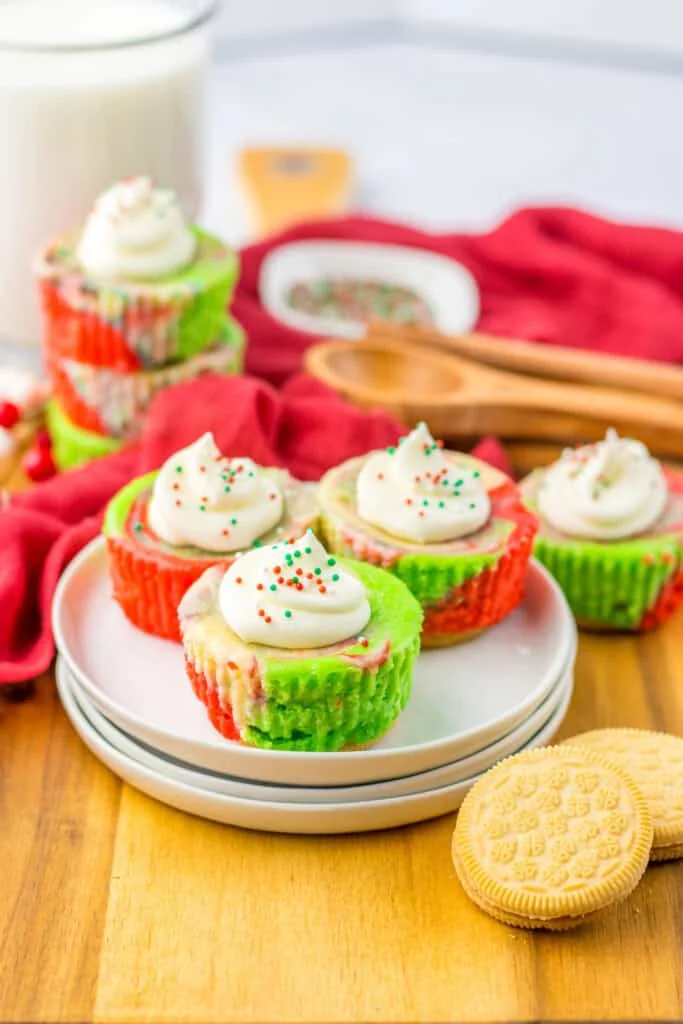 Festive Christmas cupcakes decorated with green and red wrappers, sprinkles, and whipped topping for the holidays.