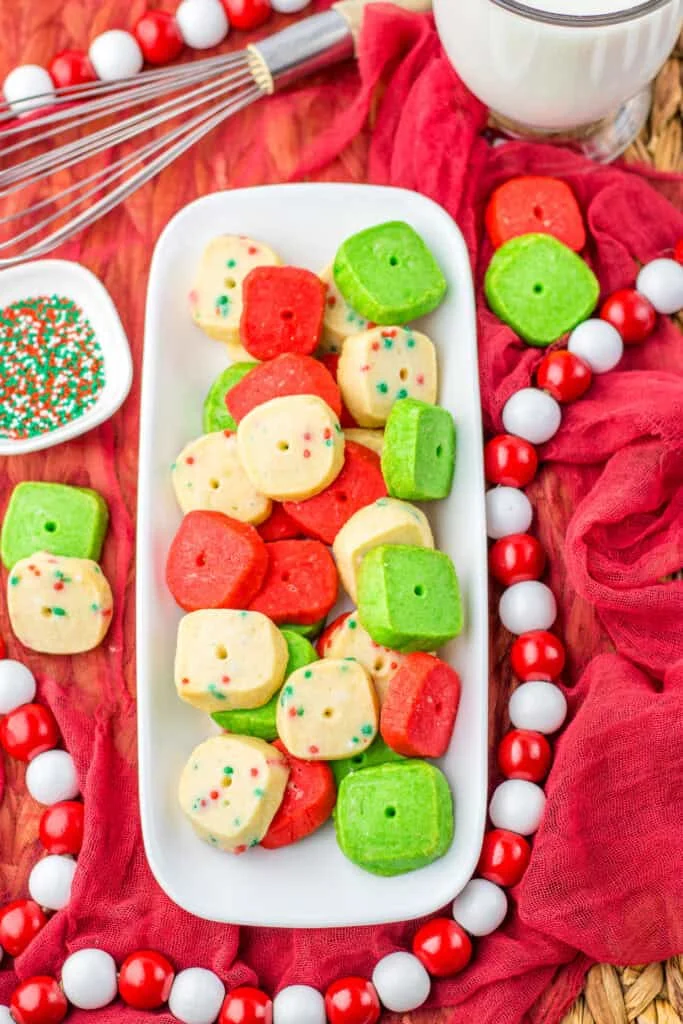mini christmas cookies on white platter, red cloth, christmas beads
