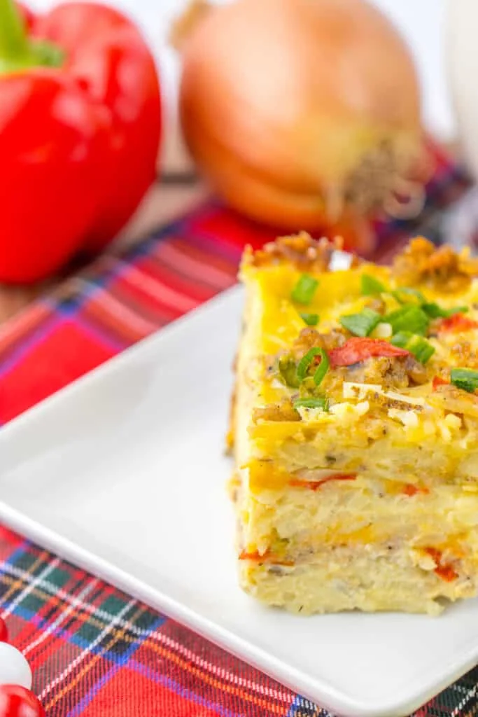 slice of casserole on white plate, onion and tomato