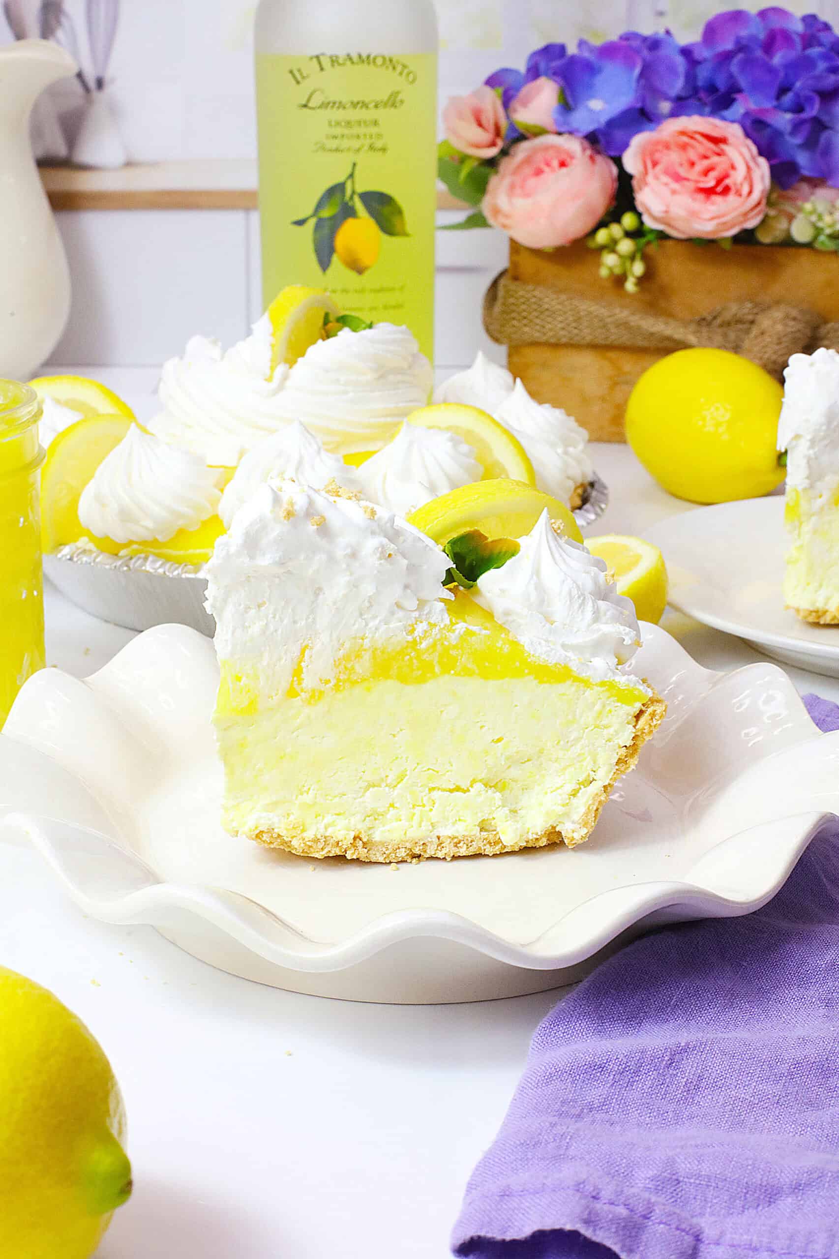 Limoncello Cream Cheese Pie with lemon slices and whipped cream on a decorative plate.