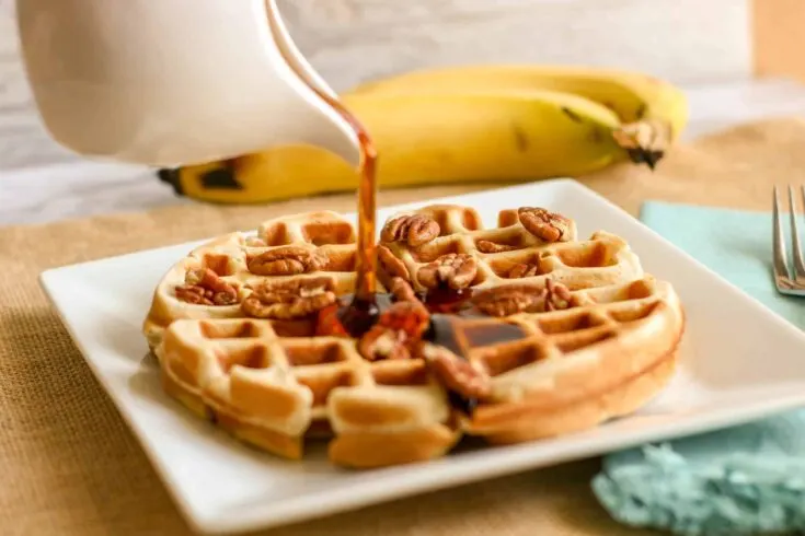 Delicious waffles topped with pecans, drizzled with syrup, perfect for breakfast or brunch.