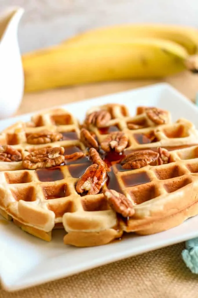 banana waffle on plate with syrup and nuts