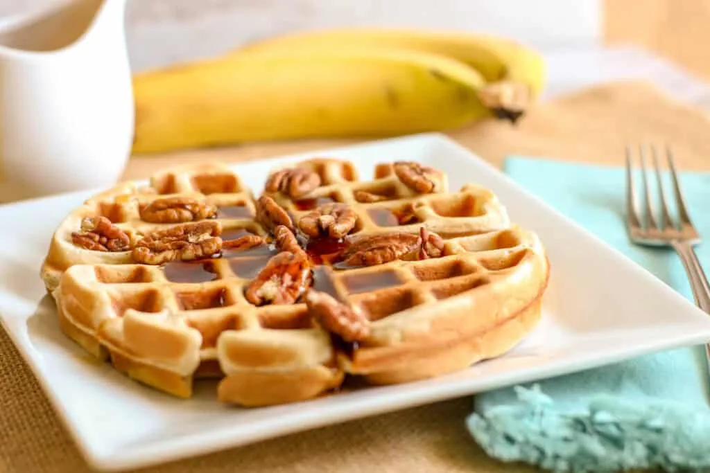 Delicious homemade waffle topped with pecans and syrup, perfect for breakfast or brunch.