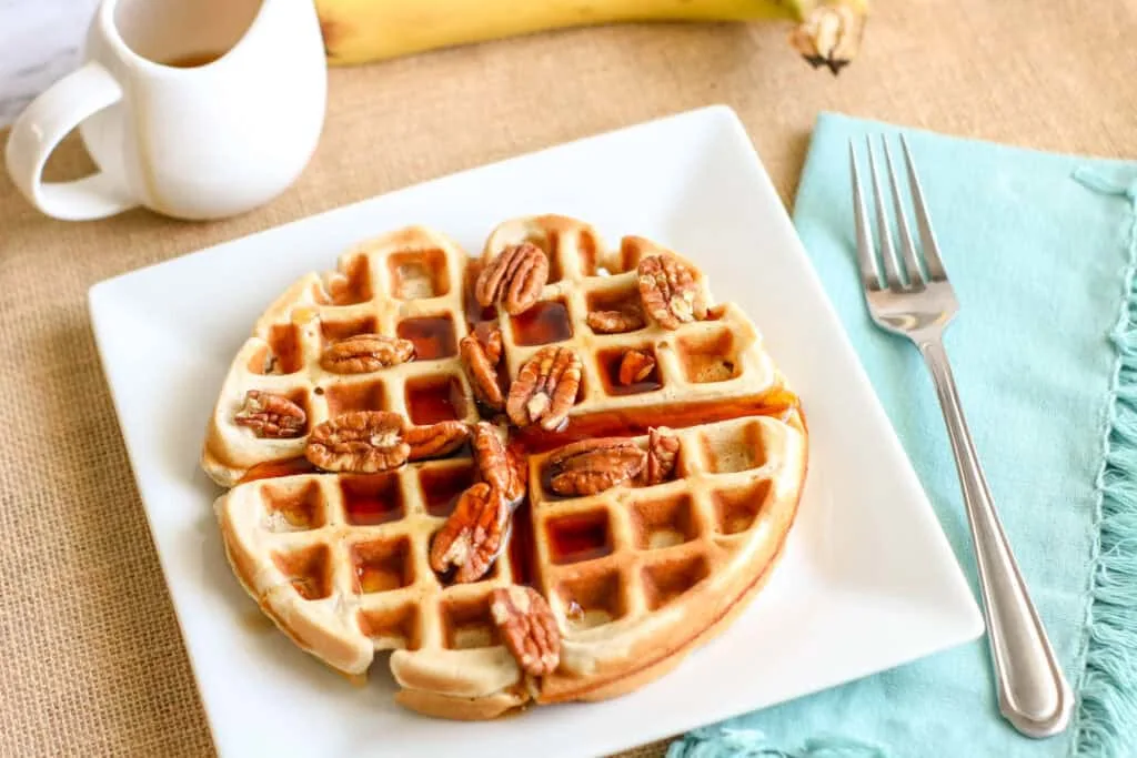 banana waffles with syrup and nuts breakfast dish.