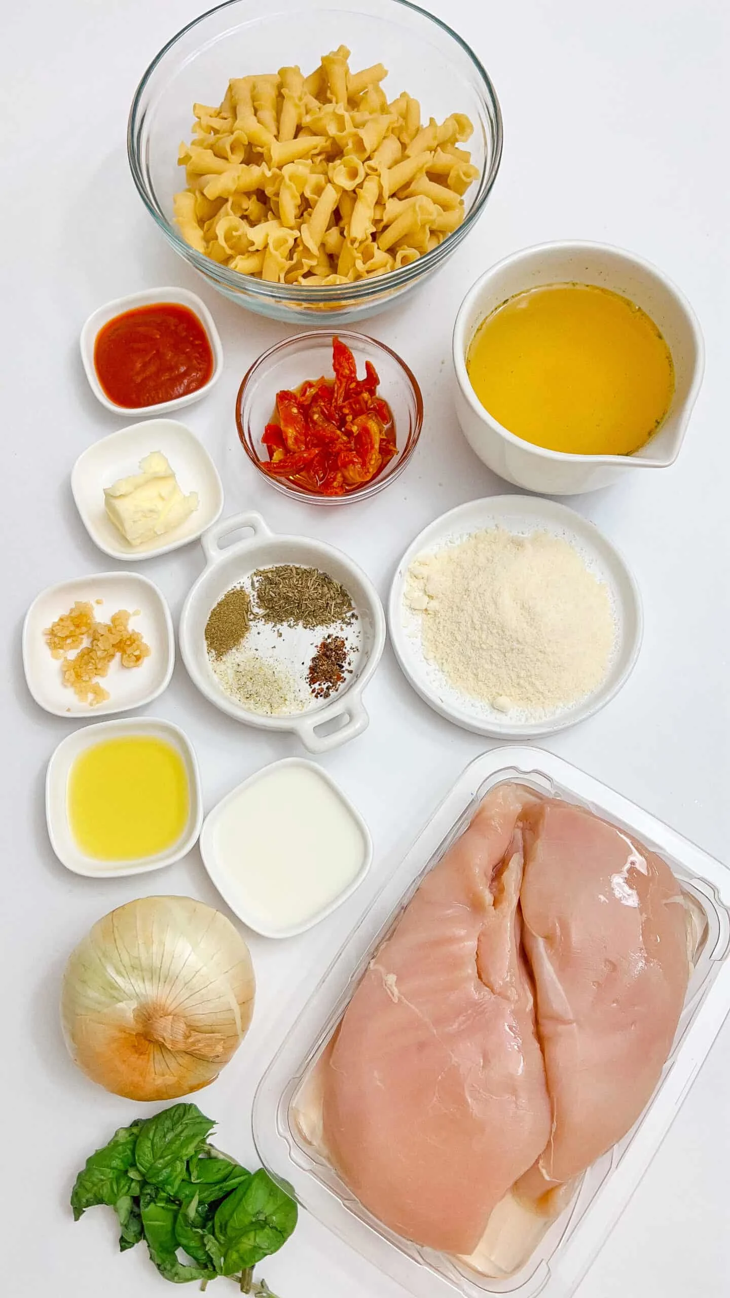 Delicious pasta with chicken ingredients including pasta, chicken, garlic, spices, and vegetables, ready to cook.