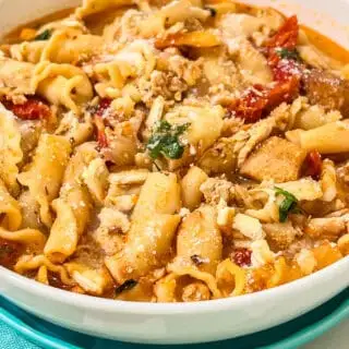 Delicious chicken pasta soup topped with cheese, sun-dried tomatoes, and herbs, perfect for family dinners.