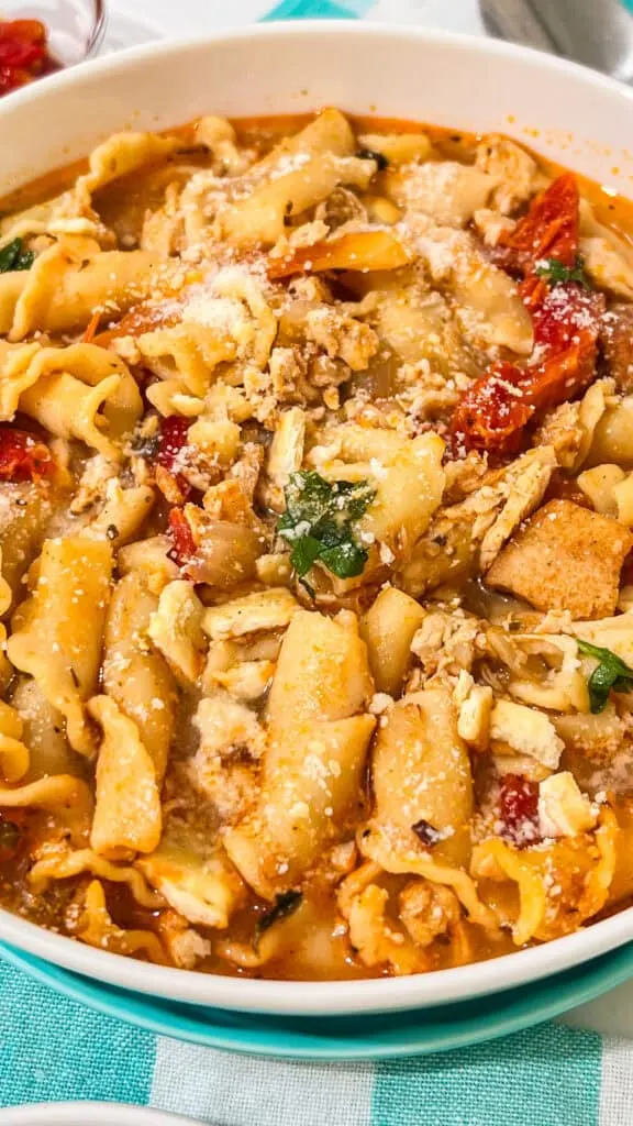 Delicious homemade marry me chicken soup in a savory broth with vegetables and grated cheese on top.