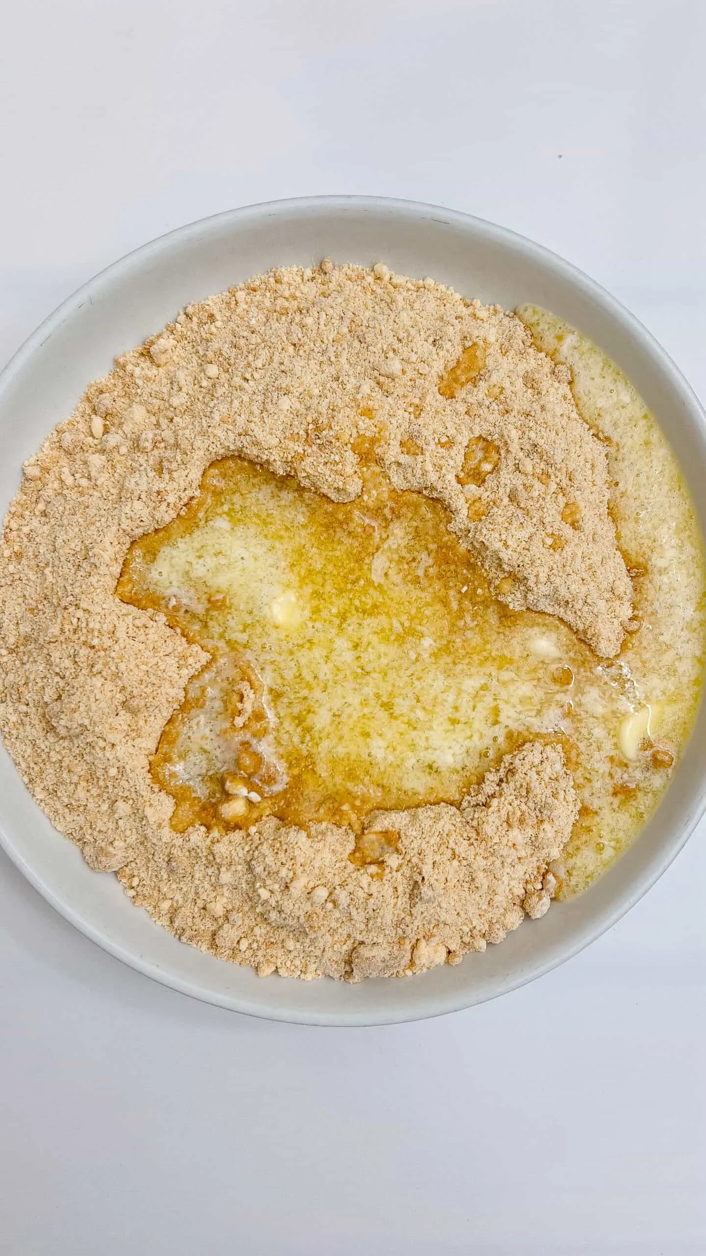 making graham cracker crust in white bowl.