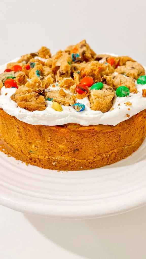 Decorative cookie cheesecake cake topped with colorful candies and whipped cream.