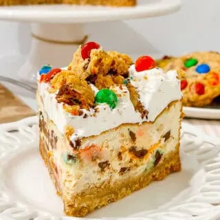 Delicious Monster Cookie Cheesecake with candy decorations, cookies and whipped cream frosting for celebrations.