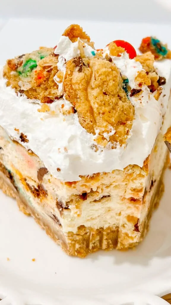 Delicious monster cookie cheesecake topped with whipped cream, sprinkles, and cookie pieces, perfect for celebrations.