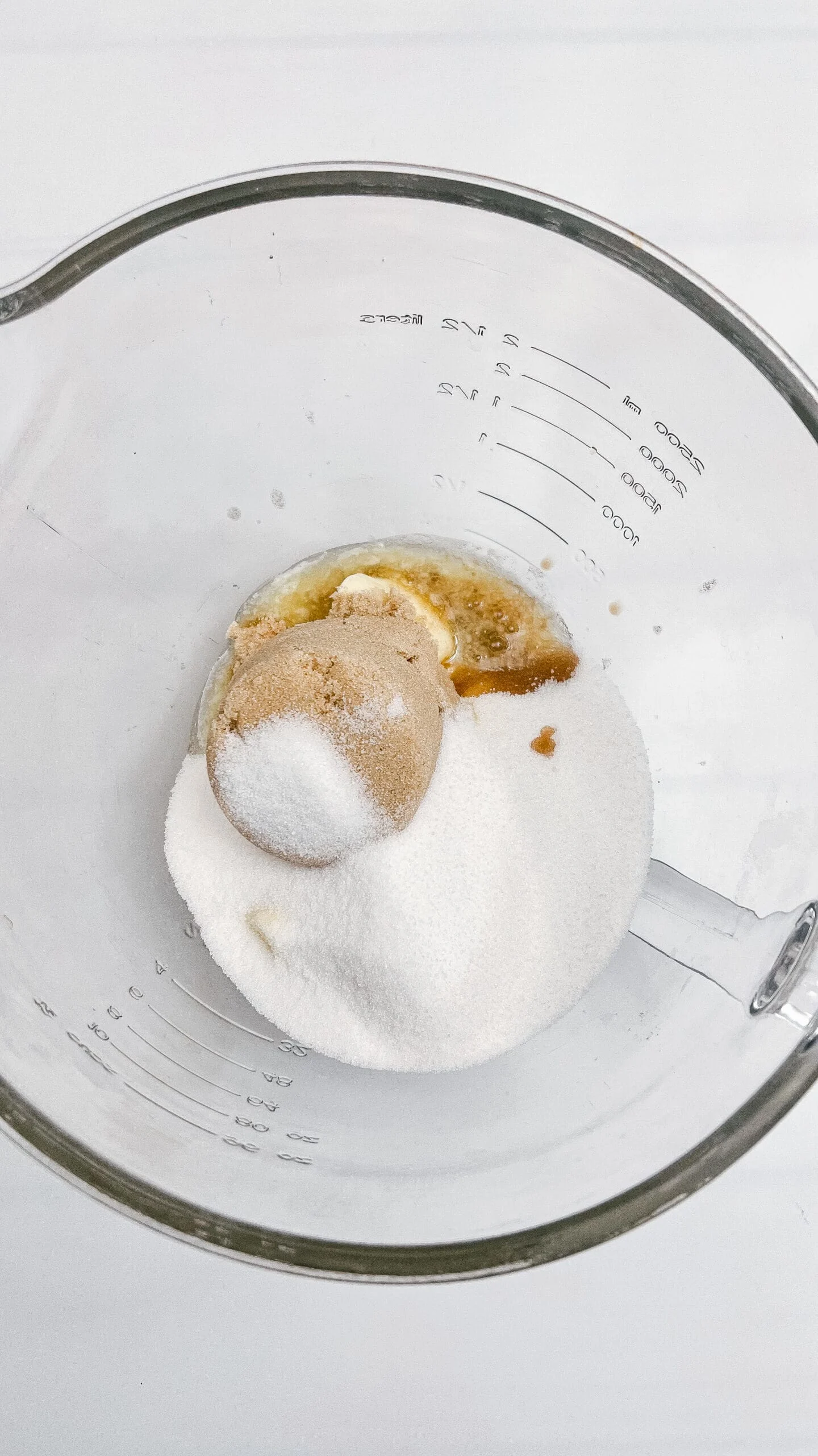Alt text: Ingredients including sugar, butter, and vanilla in a glass bowl for baking.