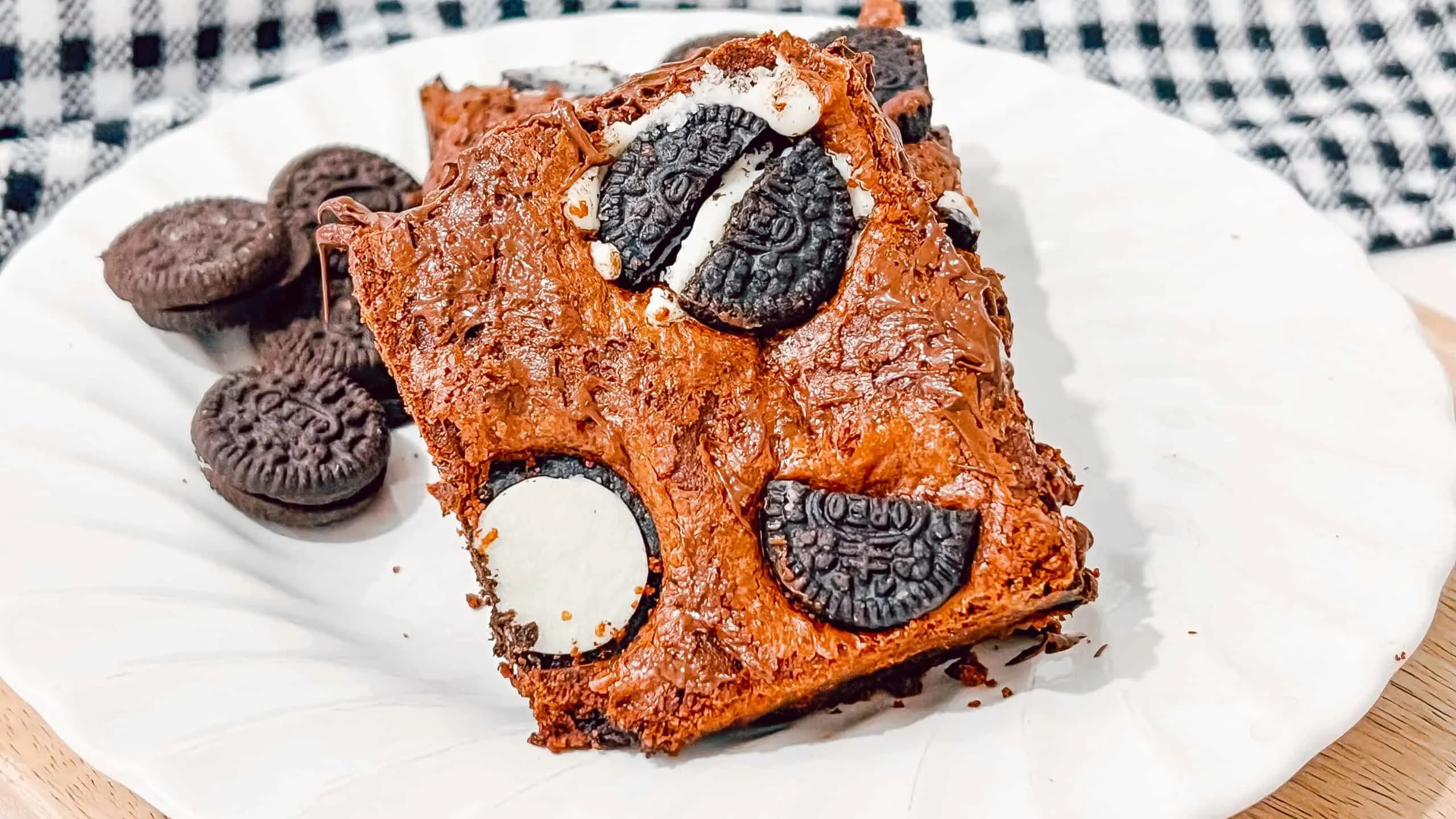 Delicious Oreo brownie with creamy Oreo chunks and rich chocolate flavor on a white plate. Perfect for dessert or snack.