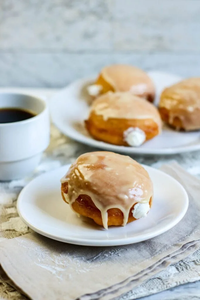 Plate of donuts on white plate served with cup of coffee