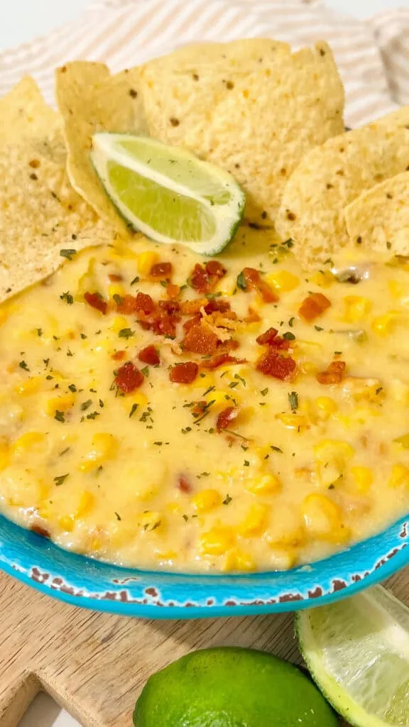 corn dip served in blue bowl with xtra bacon and lime