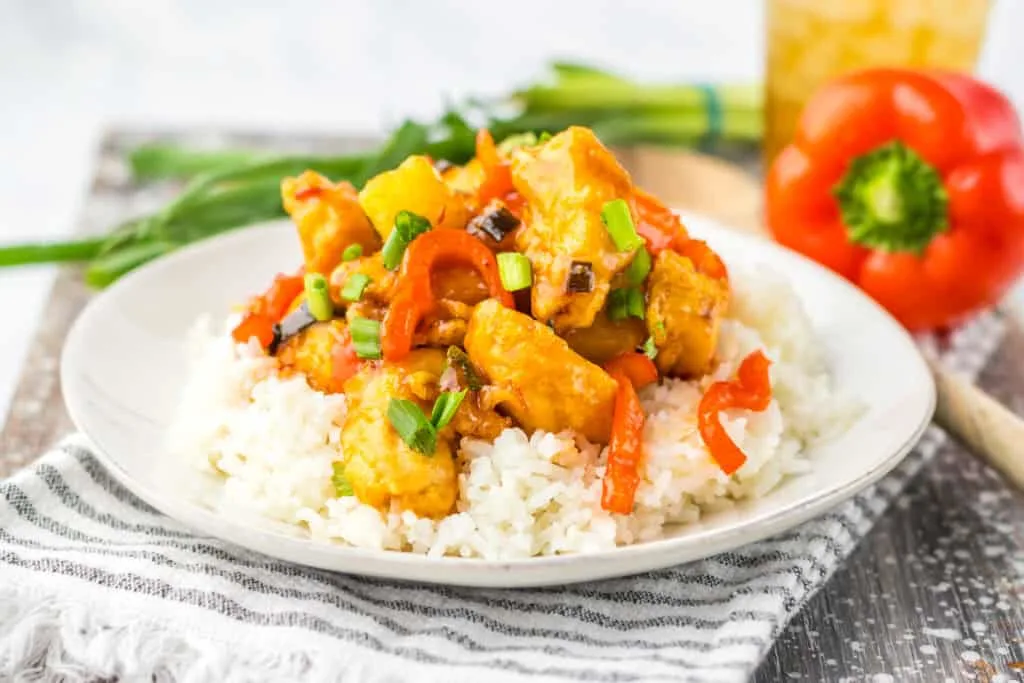 sweet chili chicken and veggies over rice on white plate horizontal