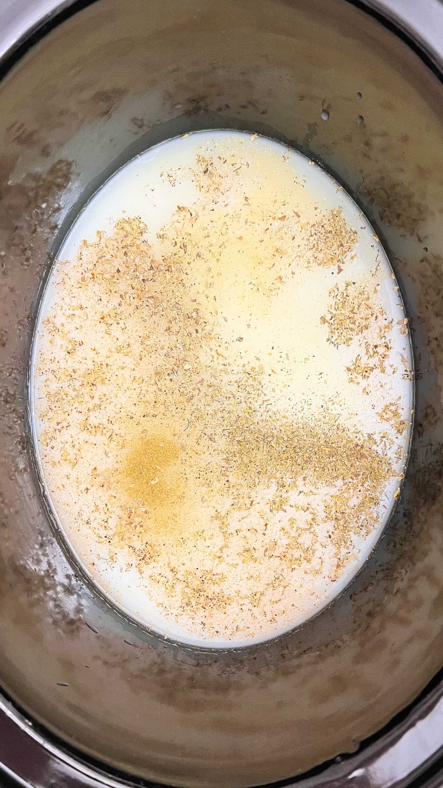 Creamy chicken Alfredo lasagna soup in a slow cooker with cheese and herbs.