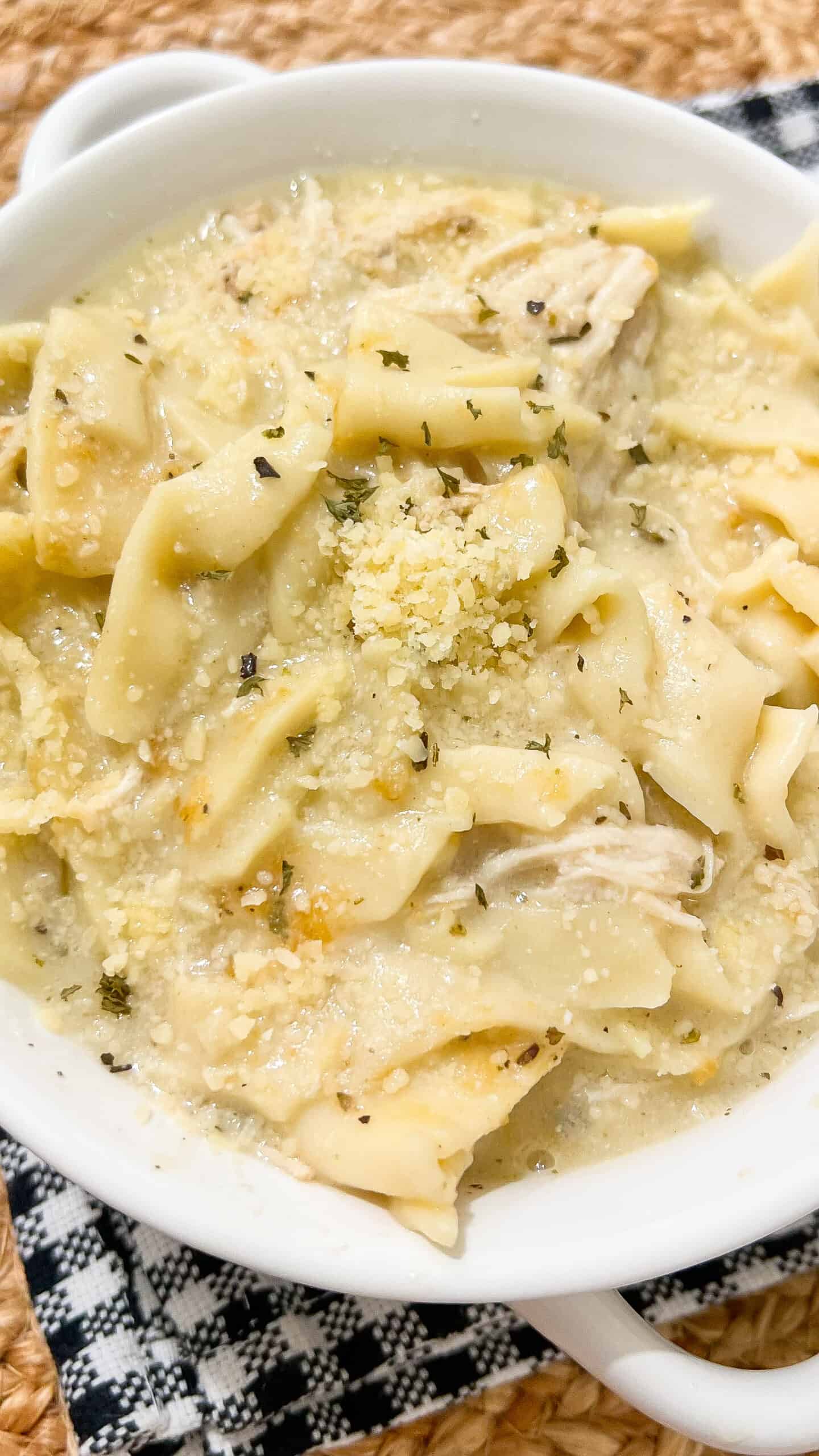 Delicious creamy chicken Alfredo lasagna soup in a white bowl with cheese and herbs.