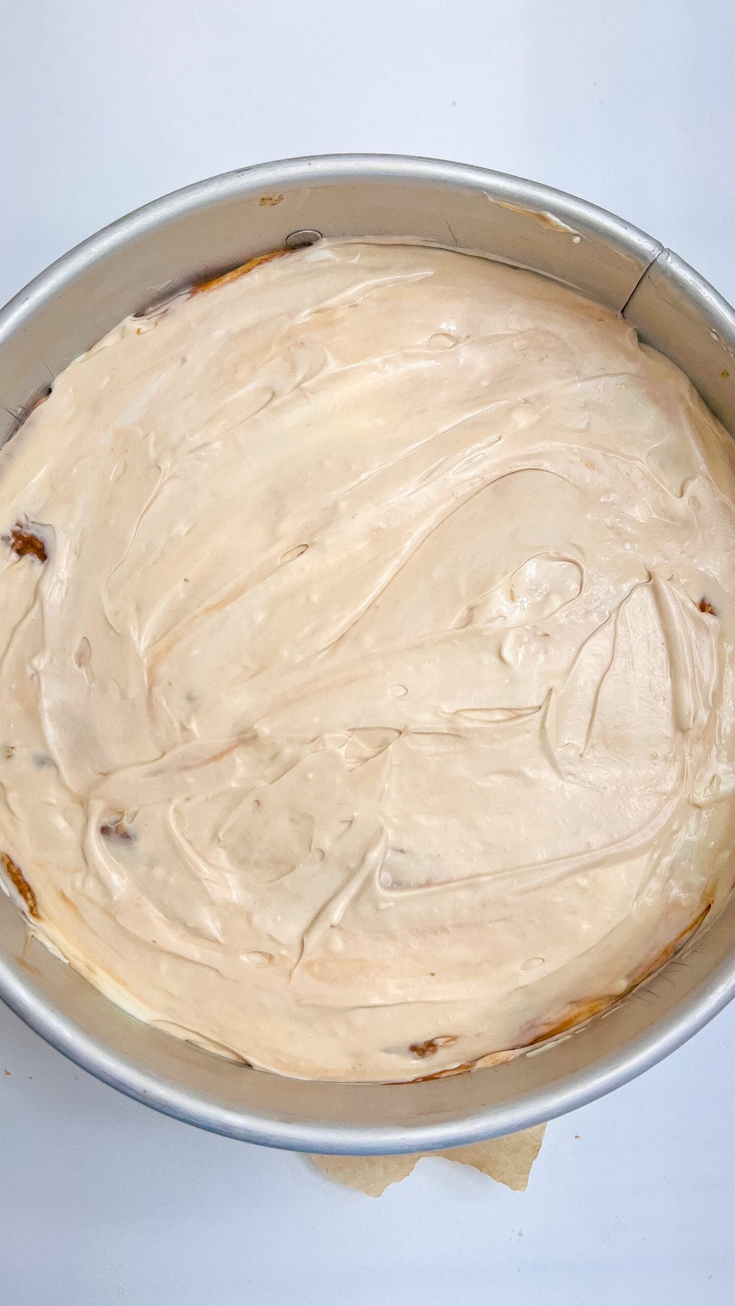 Creamy Muddy Buddy Cheesecake in a round pan, ready to chill.