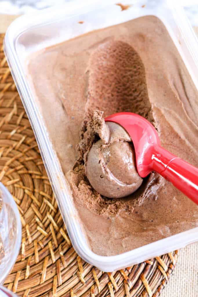 chocolate ice cream in plastic tub red scooper 