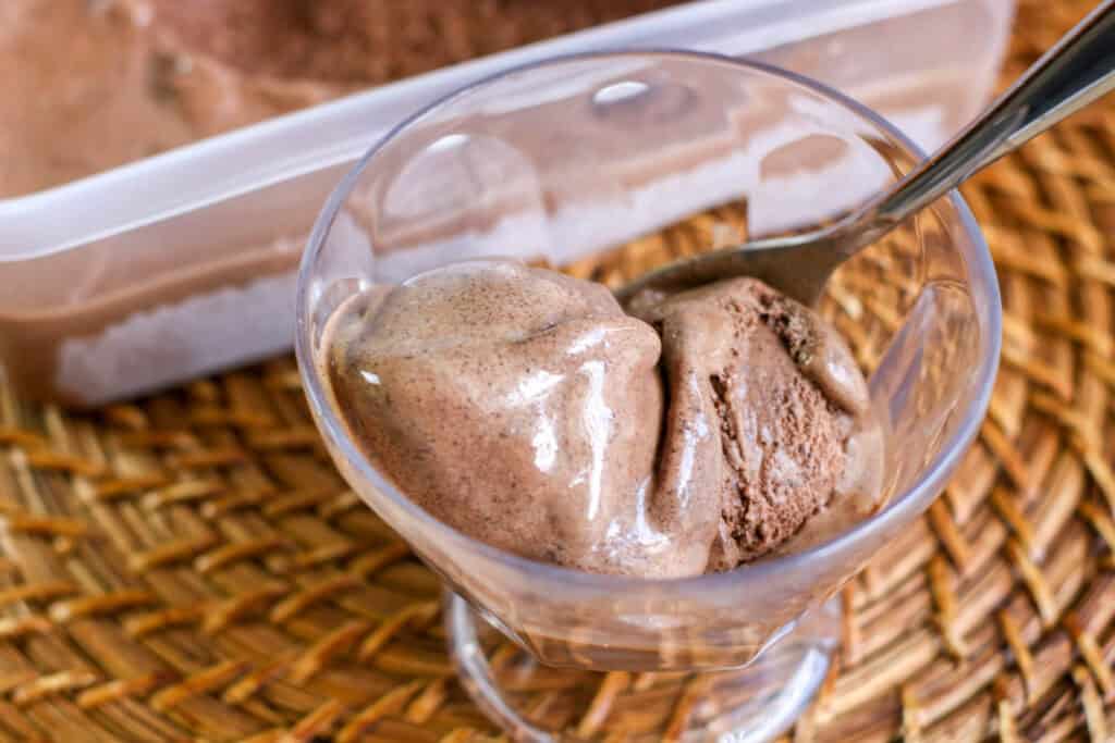 chocolate ice cream in plastic tub red scooper ,bowl of chocolate ice cream