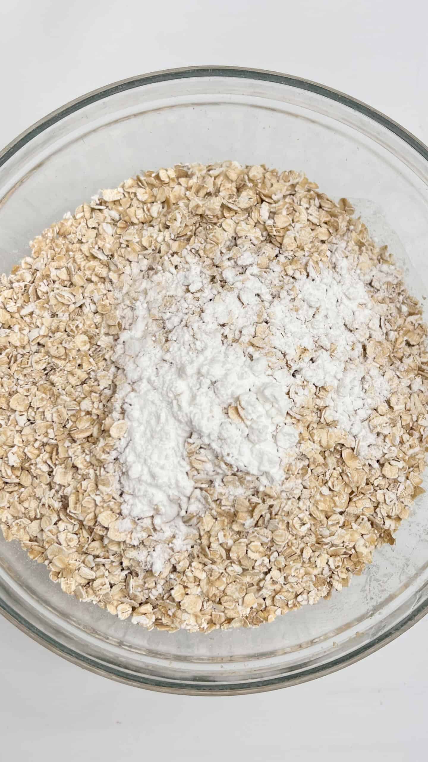 Oats and flour in a glass bowl for lemon cheesecake crust preparation.