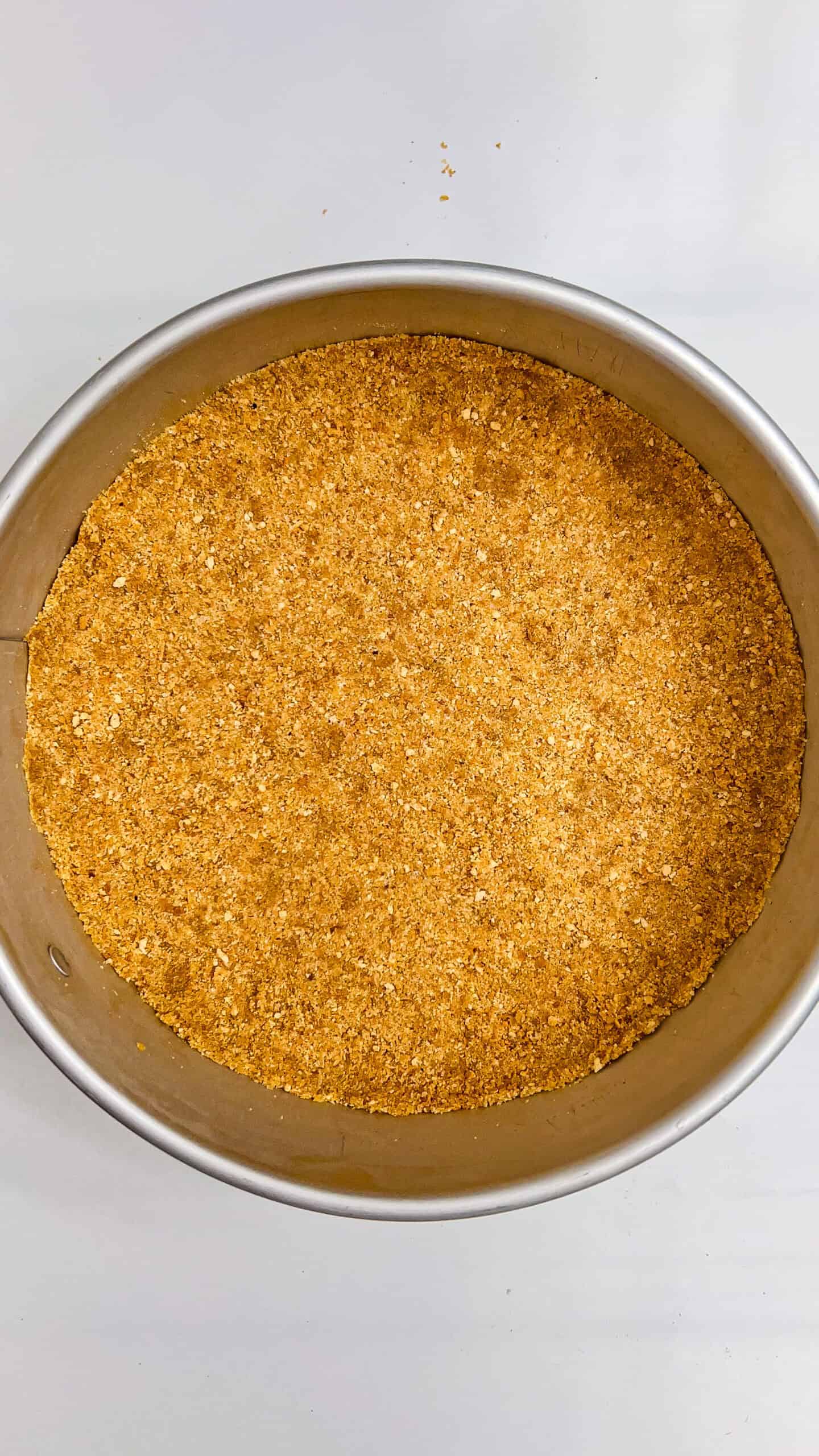 Close-up of a golden graham cracker crust in a round baking pan.