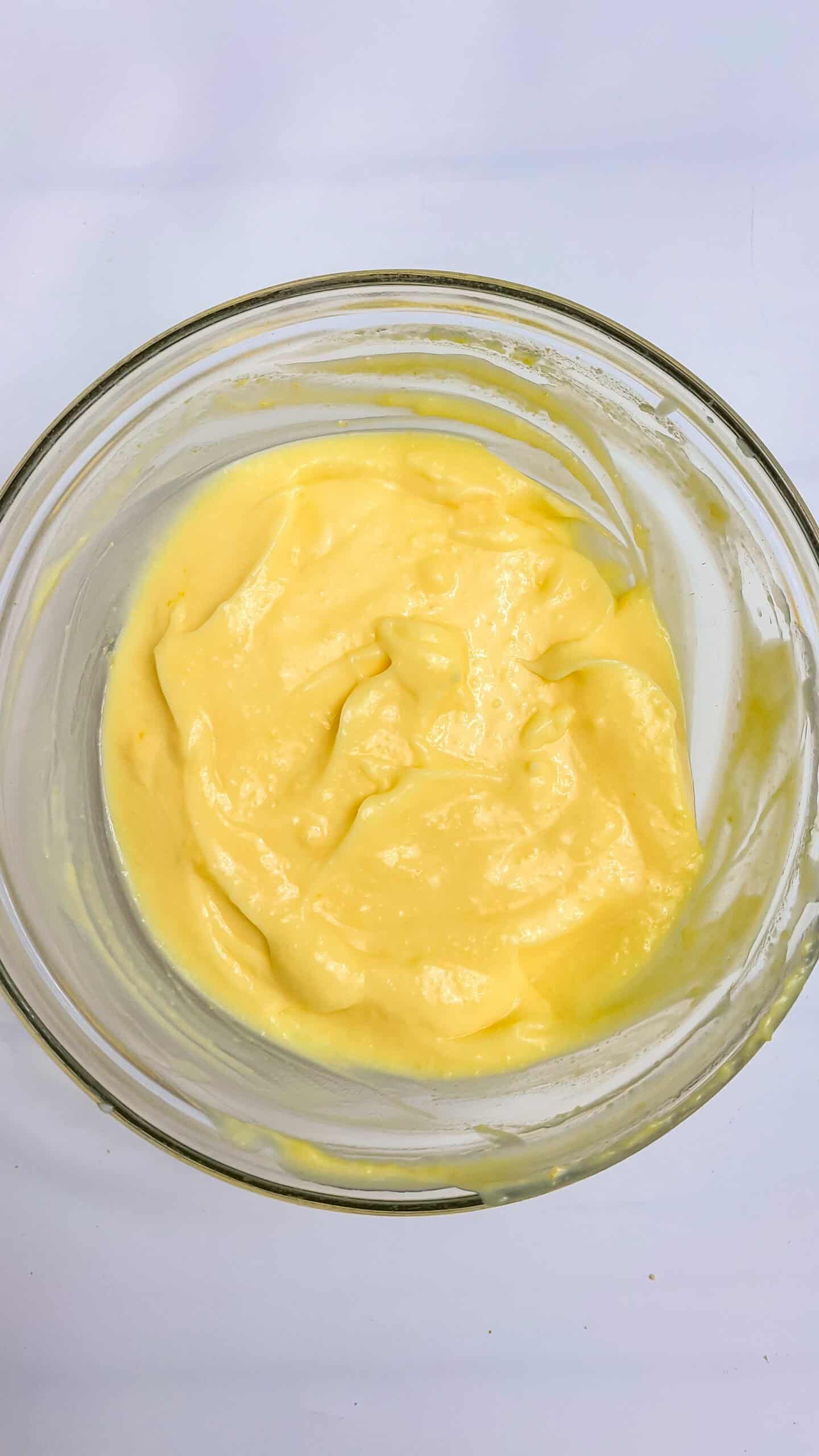 Smooth yellow custard in a glass bowl for Boston Cream Pie Cheesecake.