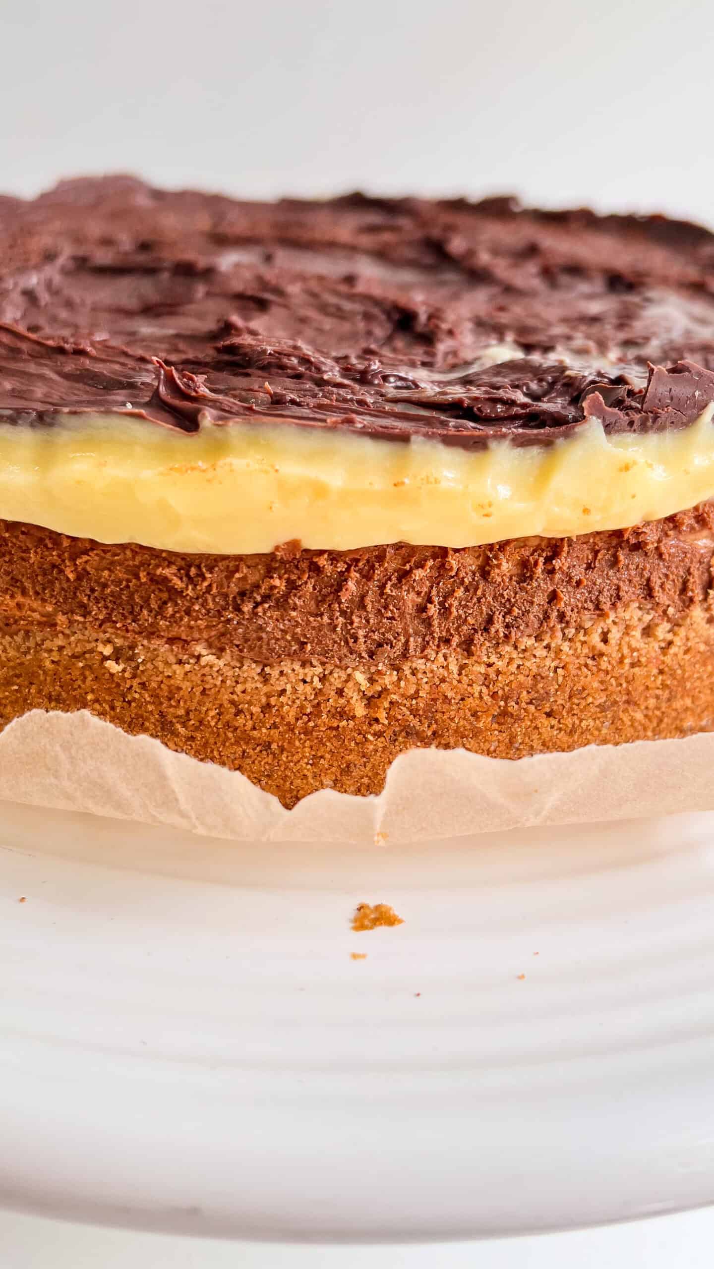 Close-up of Boston Cream Pie Cheesecake with chocolate topping and custard filling.
