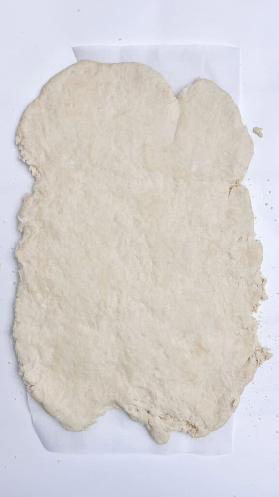 Homemade Rolled out Biscuit dough on parchment paper, ready for baking.