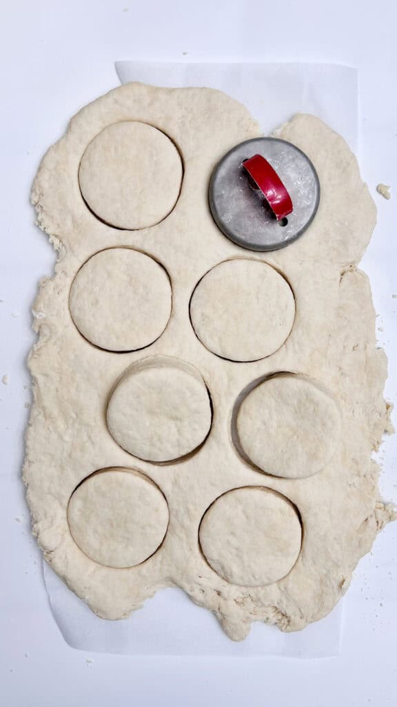 Round cookie cutter pressing into rolled dough for biscuits.