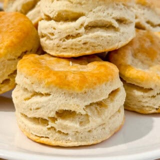 Freshly baked homemade buttermilk biscuits on a white plate.
