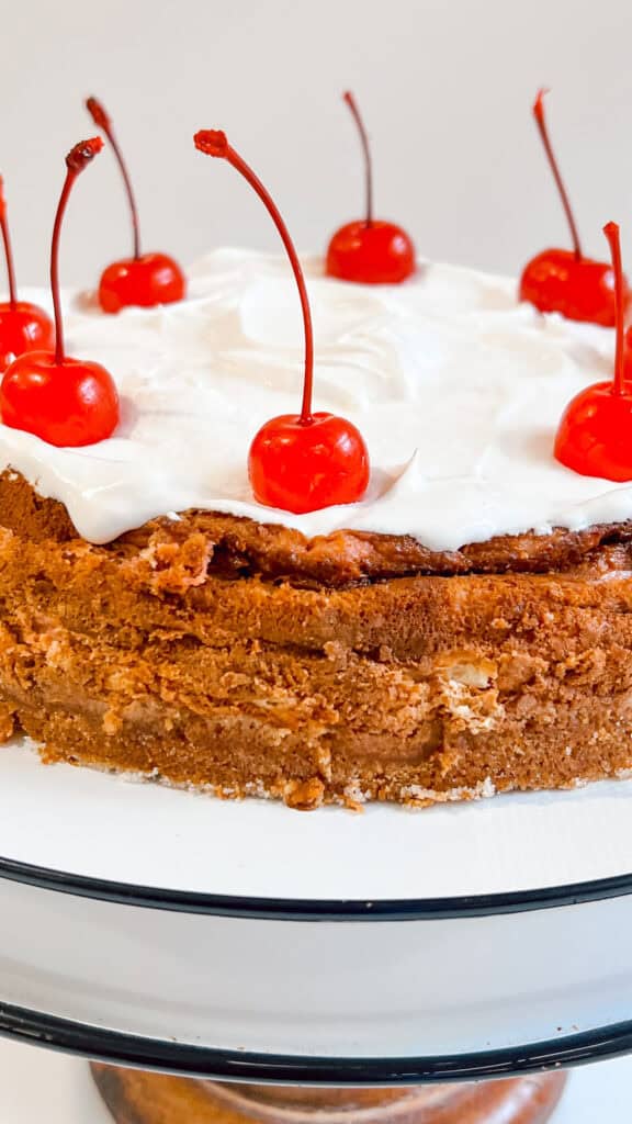 Cherry Coke cheesecake topped with fresh cherries and white frosting.