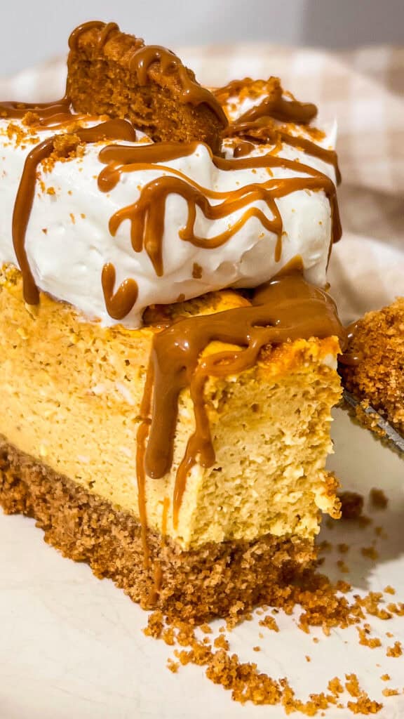 Close-up of pumpkin Biscoff cheesecake with caramel drizzle and cookie topping.